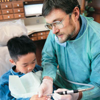 Pediatric dentist treating young boy