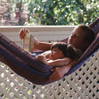 Older brother reading to younger brother in a hammock