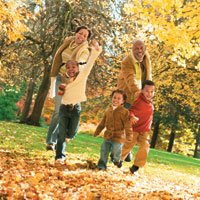 Grandparents and grandchildren playing outside in autumn leaves