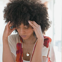 Woman looking down holding forehead with hands