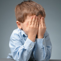 Boy covering his face with his hands