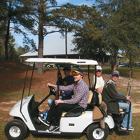 Participants at Annual Shoot for the Cure Fundraiser ride in golf cart