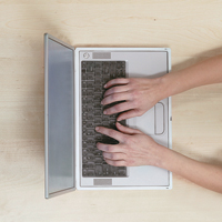 overhead shot of person's hands typing on laptop