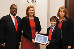 Young boy and mother present award to Senator Chris Coons
