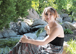 girl sitting outside with rocks in background