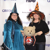 Two women wearing witch hats holding a teddy bear
