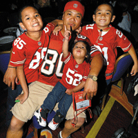 Man with three young boys wearing matching red jerseys