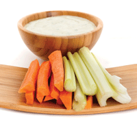 Sliced carrots and celery presented with bowl of creamy dressing