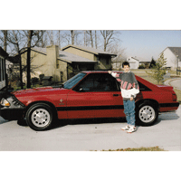Ryan White standing in front of red Mustang car