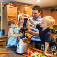 Family using juicer to make juice in kitchen