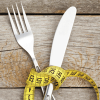 Knife and fork tied with yellow measuring tape