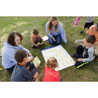 Adults and children sitting on grass doing learning activity