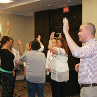 Group of adults with hands raised during ice breaker activity