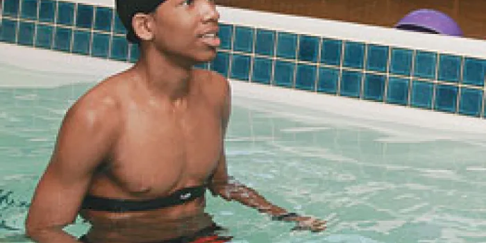 Boy with hemophilia exercises in a pool