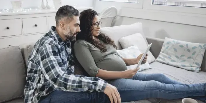 Pregnant woman and man looking at laptop computer