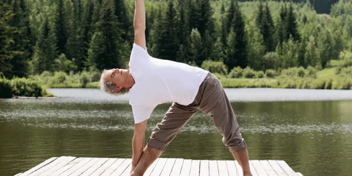 Man doing yoga by a lake
