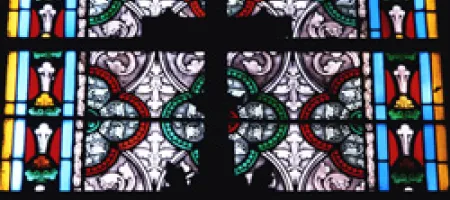 Cross in front of church stained glass window