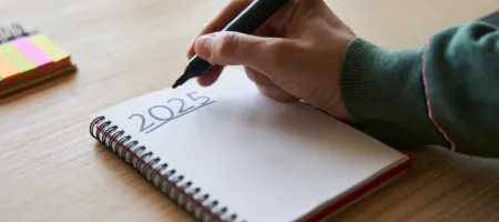 A person writing their plans and goals for 2025