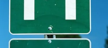 Green street sign with capital letter "H" and arrow pointing right underneath