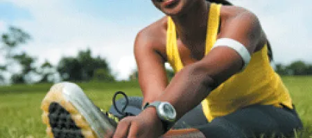 Athletic woman sitting on the grass, stretching