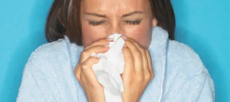 Woman blowing nose into tissue