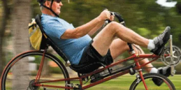 Older man wearing helmet riding recumbent bike